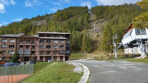 A multi-story hotel with balconies, a ski lift, and a forested hillside in the background. - Studio 4 Personnes Avec Balcon aux Pieds des Remontées Mécaniques (Allos)
