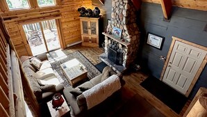 A cozy cabin interior with a stone fireplace, wooden furniture, and large windows. - Beautiful log home-dog friendly, creek & mountain views,close to national parks (MAMMOTH CREEK)