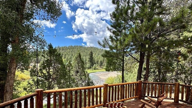 A wooden deck with a railing, overlooking a river and forested area. - Beautiful log home-dog friendly, creek & mountain views,close to national parks (MAMMOTH CREEK)