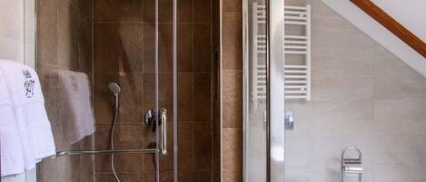 A modern bathroom with a glass-enclosed shower, a white toilet, and a towel rack.