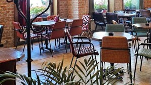 A restaurant with brick walls, wooden beams, and a chandelier. Tables and chairs are arranged for dining. - Villa 1927 (Belgrade)