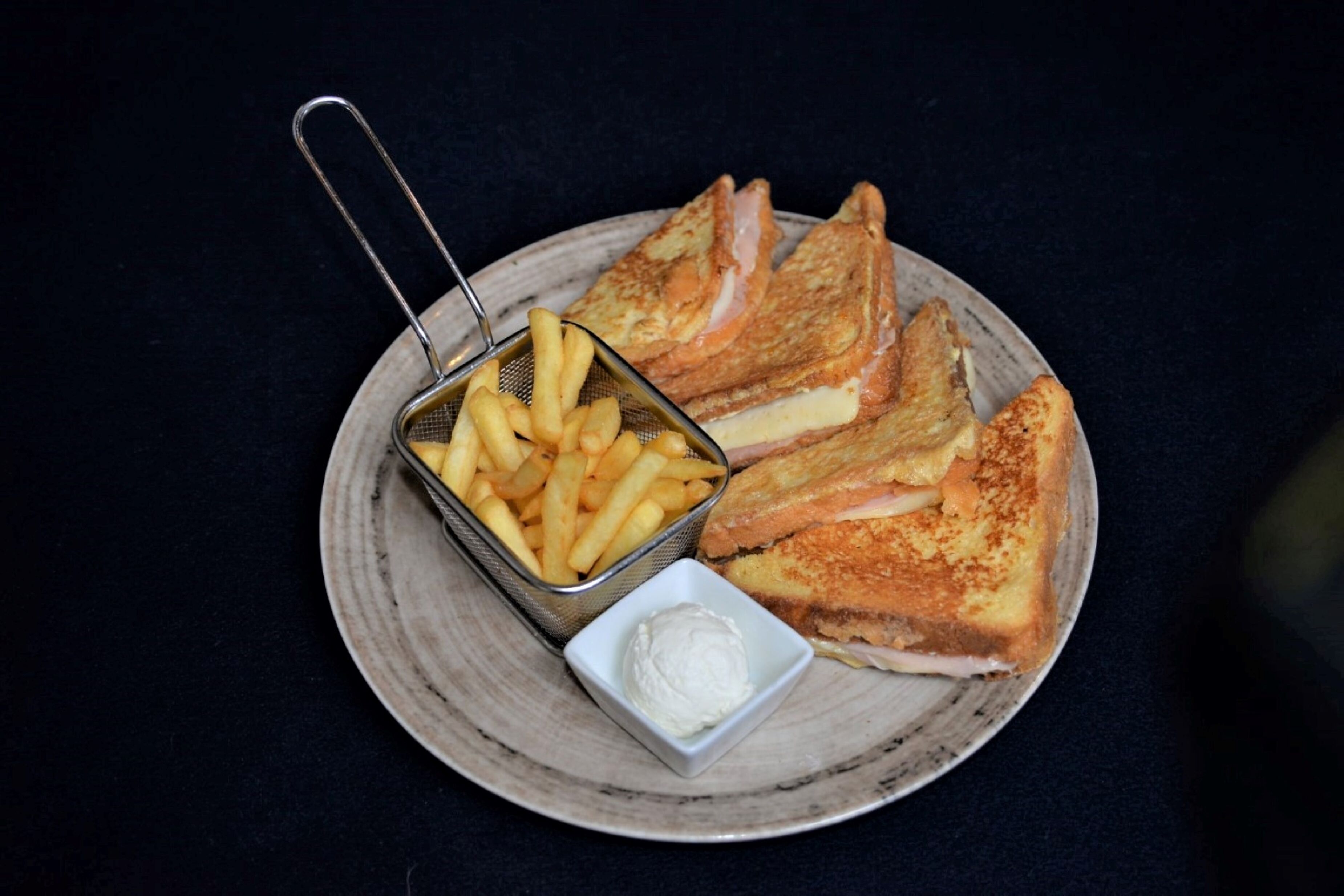 Un plato con tostadas francesas, un recipiente pequeño de papas fritas y un cuenco pequeño de mantequilla.