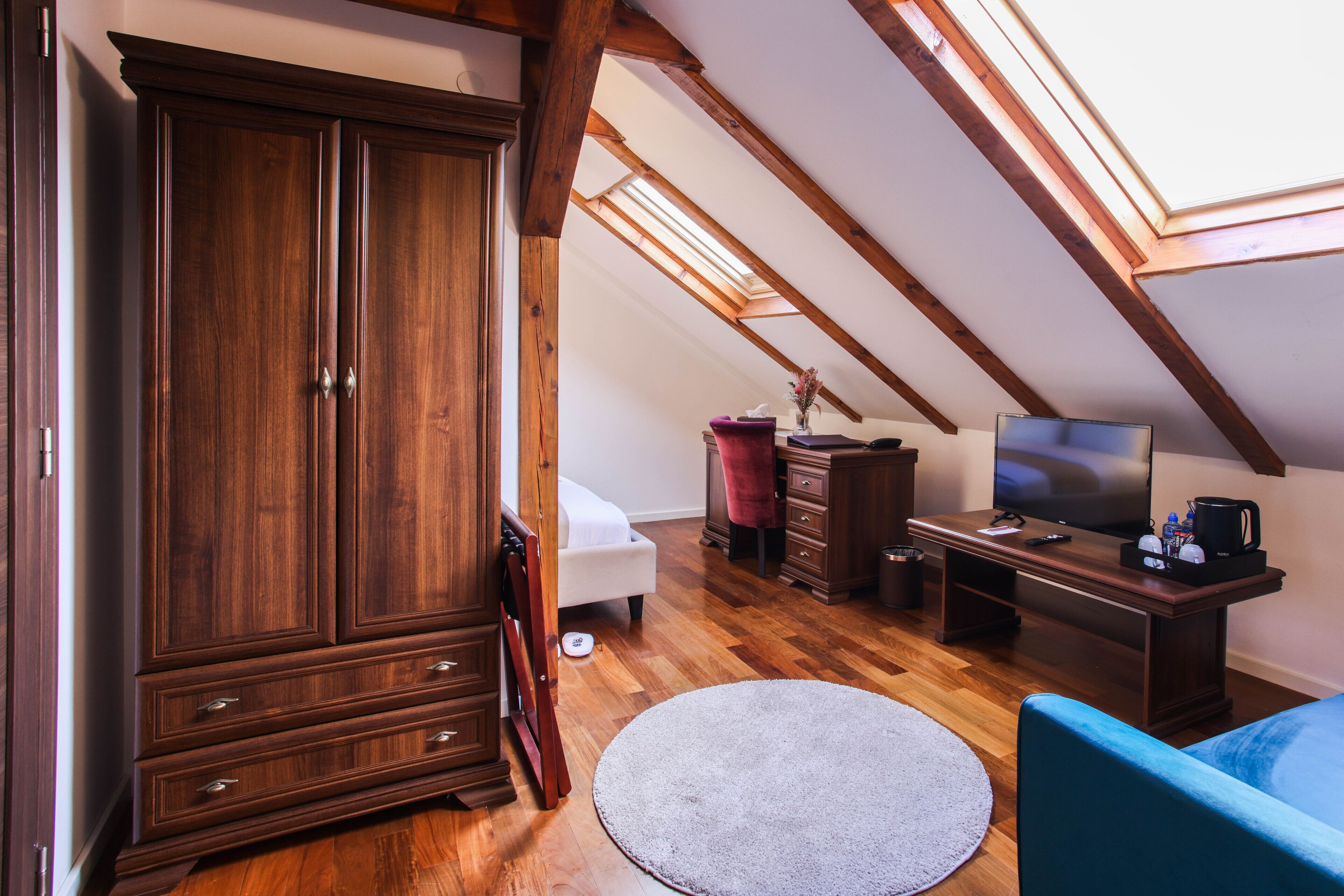 Une chambre de style « loft », dotée d’une grande armoire, d’un lit, d’un bureau avec une télévision et d’une fenêtre de toit.