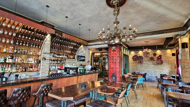 A bar area with a variety of liquor bottles, a counter with a bartender, and seating arrangements. - Villa 1927 (Belgrade)