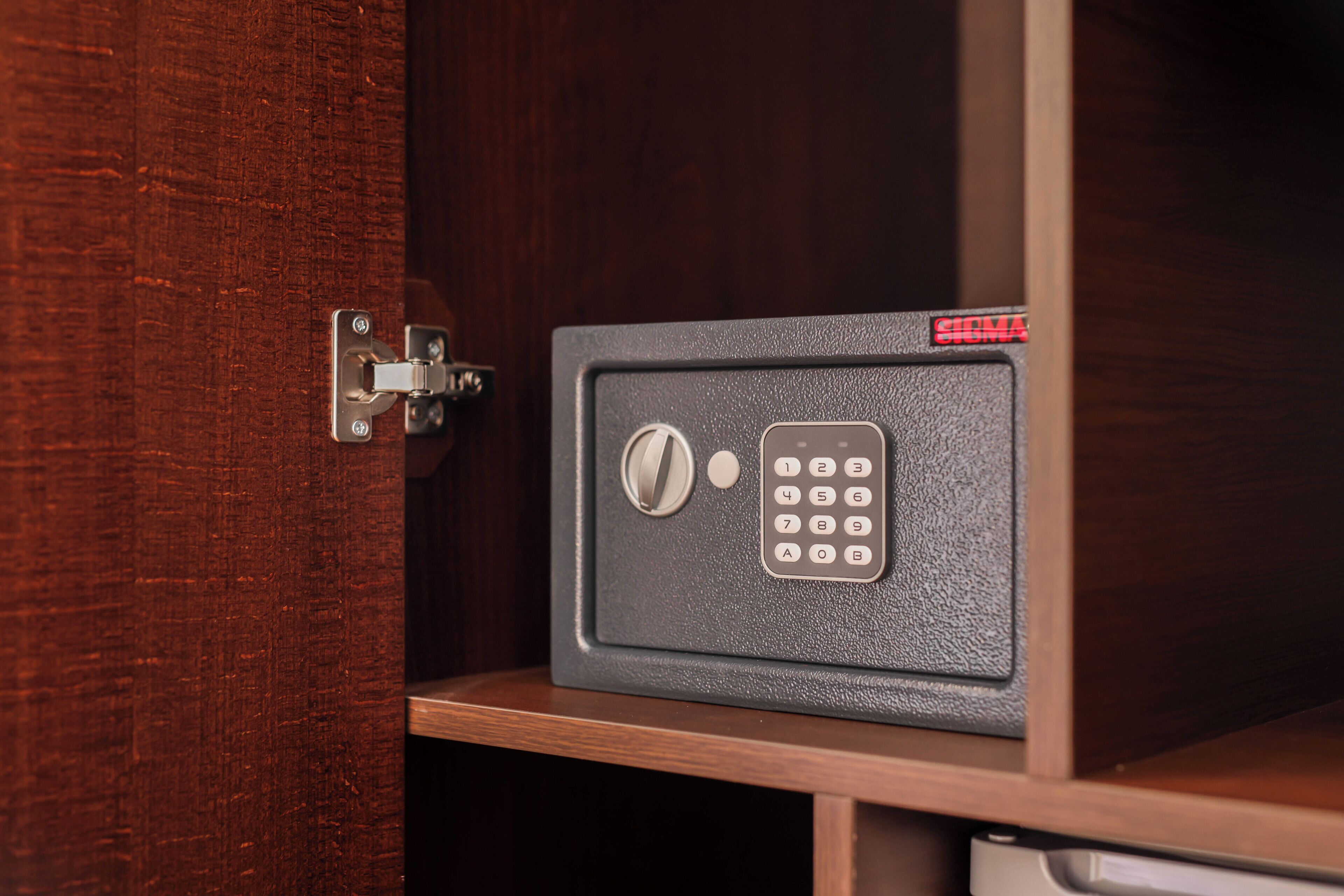 A safe with a numeric keypad and a combination lock, mounted on a wooden cabinet.