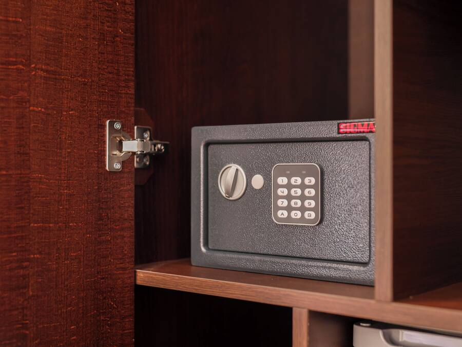 A safe with a numeric keypad and a combination lock, mounted on a wooden cabinet.