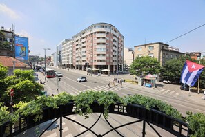 A multi-story building with a curved facade, a street with vehicles and pedestrians, and a Cuban flag. - Villa 1927 (Belgrade)