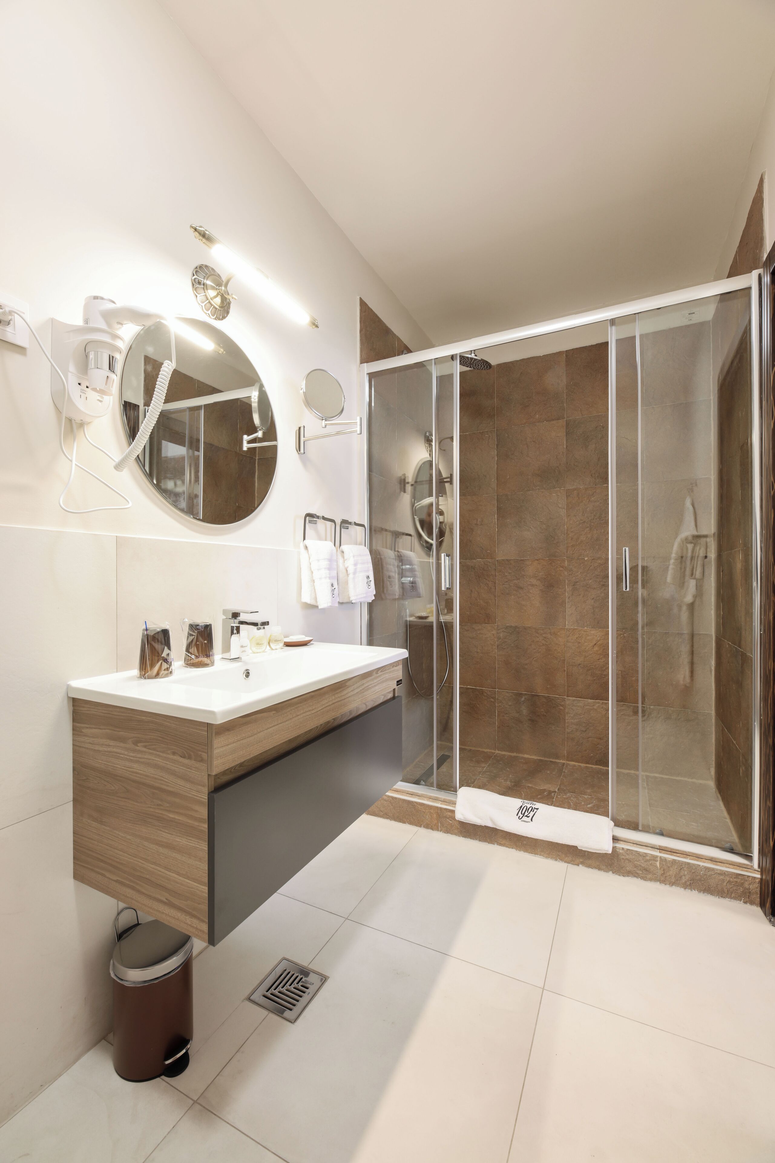Un baño moderno con tocador de madera, un espejo grande, cabina de ducha de vidrio y un perchero para toallas.