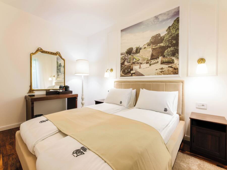 Une chambre d’hôtel avec un grand lit, une table de chevet, un miroir, une lampe et un tableau au mur.