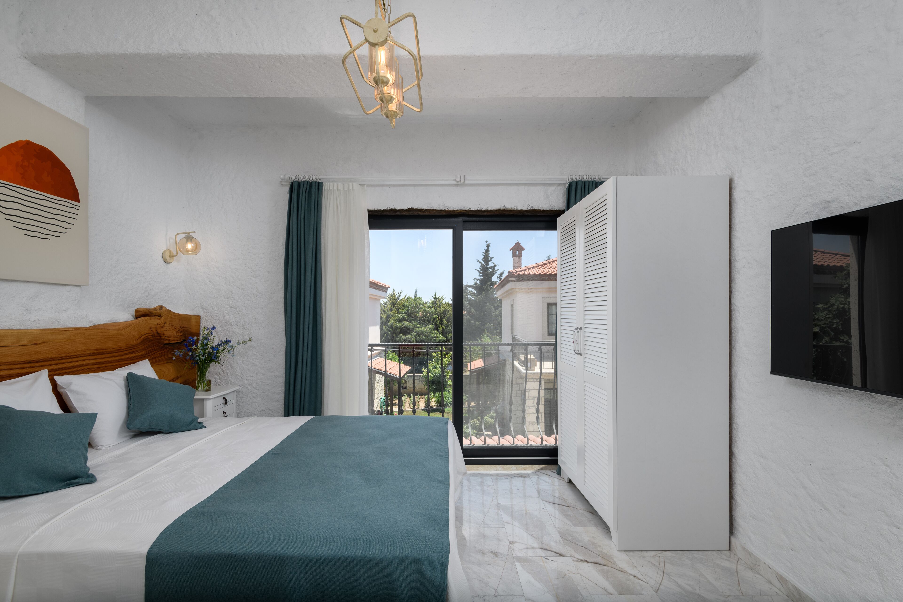 Ein Schlafzimmer mit Bett, Nachttisch, Wandleuchte, Deckenleuchte und Blick ins Freie.