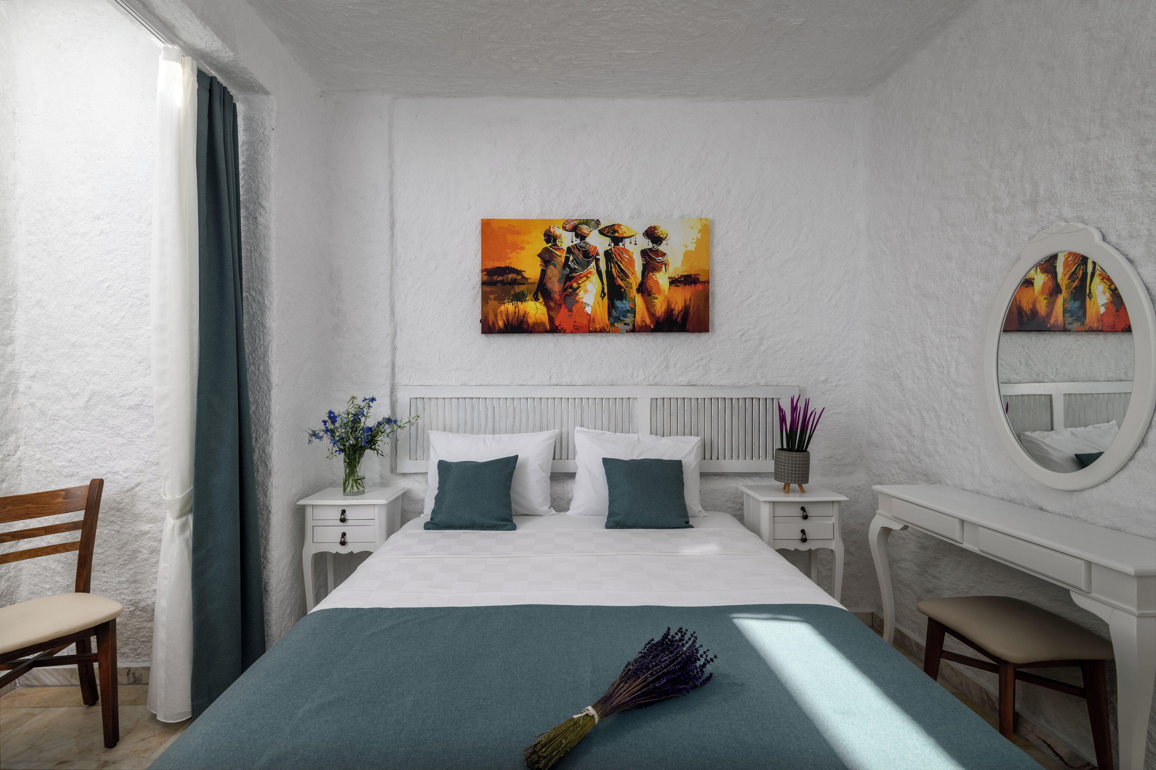 Un dormitorio con cama, mesitas de noche, cómoda, silla y un cuadro en la pared.