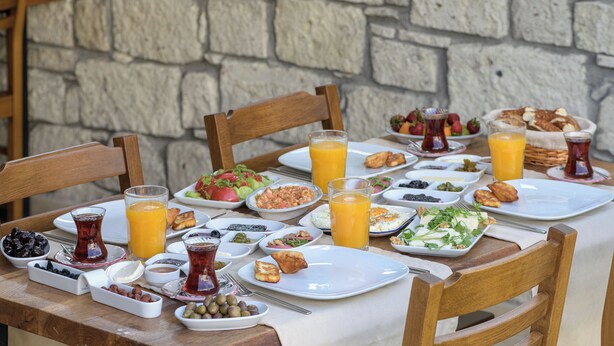 Una mesa de desayuno con diversas opciones, como frutas, bollería y bebidas.