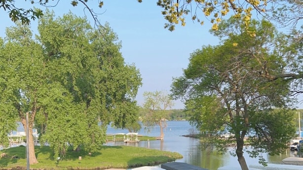 Vista para o lago com barcos atracados, árvores e um coreto.