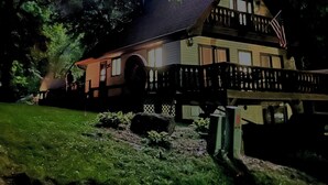 Uma casa com telhado escuro, varanda e cerca.