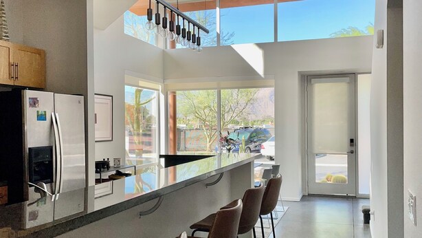 A modern kitchen with a bar area, large windows, and a door leading outside. - Modern Townhouse in Palm Springs (Palm Springs)