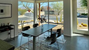 A spacious, modern interior with a high ceiling, large windows, and a dining area with a table and chairs. - Modern Townhouse in Palm Springs (Palm Springs)