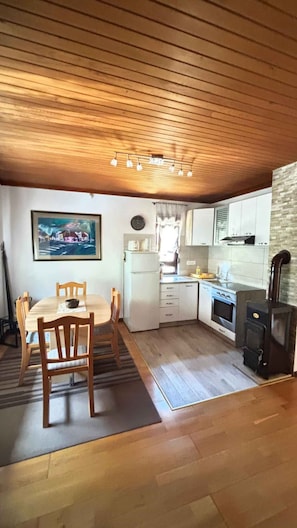 A compact kitchen with a dining area, wooden ceiling, and a painting on the wall. - Holiday home with terrace and large garden (Delnice)