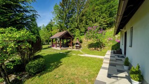 A gazebo with a stone fireplace, surrounded by a well-maintained lawn and trees.