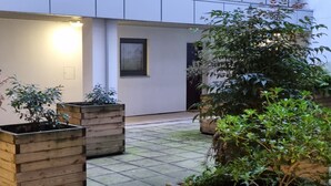 Une cour intérieure dotée d’un sol carrelé, de jardinières en bois et d’une structure de plafond moderne.