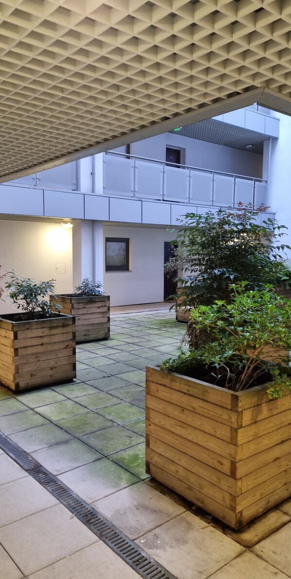 An indoor courtyard with tiled flooring, wooden planters, and a modern ceiling structure. - Apartment Sleeps 8 With Wi-fi (Birmingham)