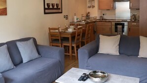 Un salon moderne comprenant deux canapés, une table basse et un coin repas avec des chaises et une table.