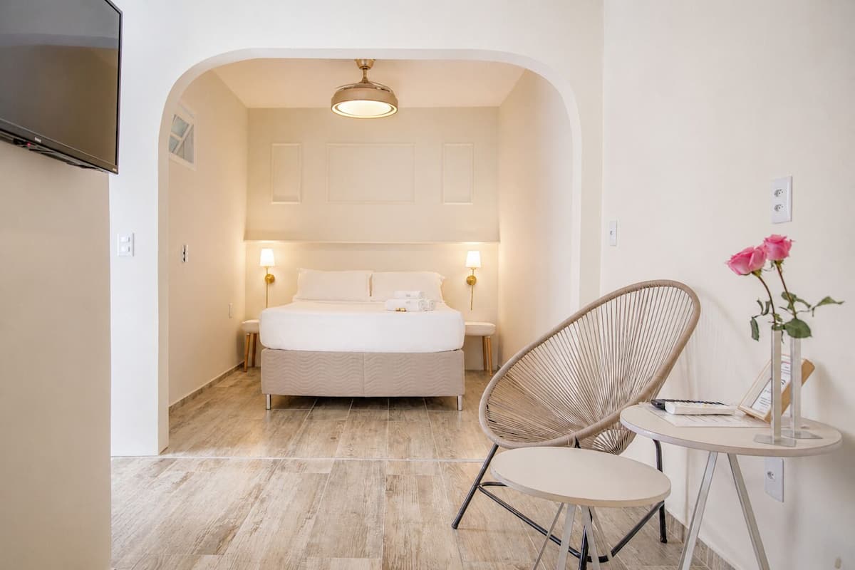 Une chambre à coucher avec un lit, des lampes de chevet, une chaise, une petite table et un ventilateur de plafond.