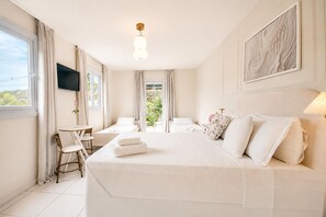 A hotel room with a bed, a desk, a chair, a TV, and a window. - ElSi Pousada (Búzios)