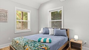 A bedroom with a bed, a nightstand, and a wall with a quote.