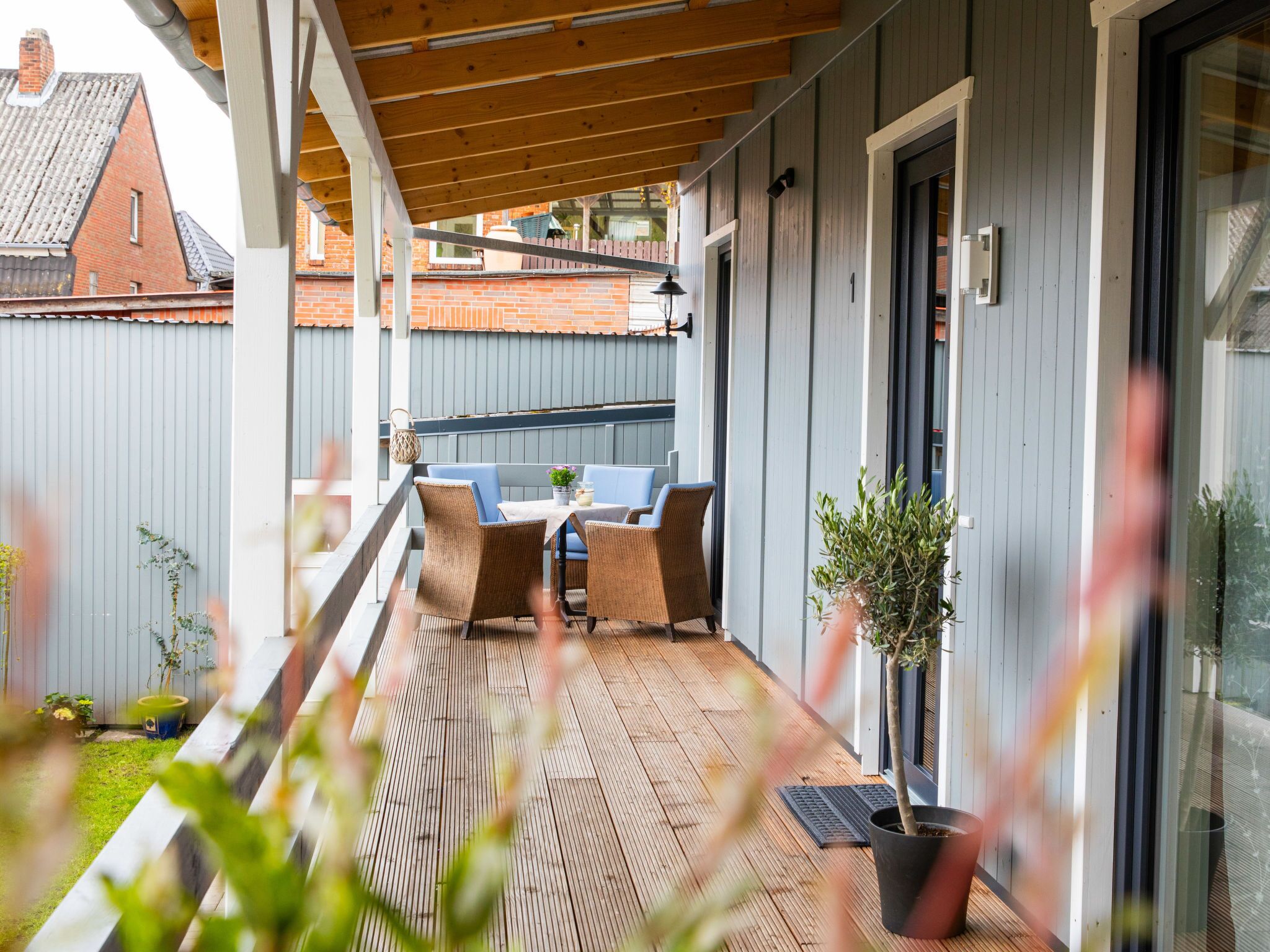 A covered outdoor seating area with wicker furniture and a potted plant.