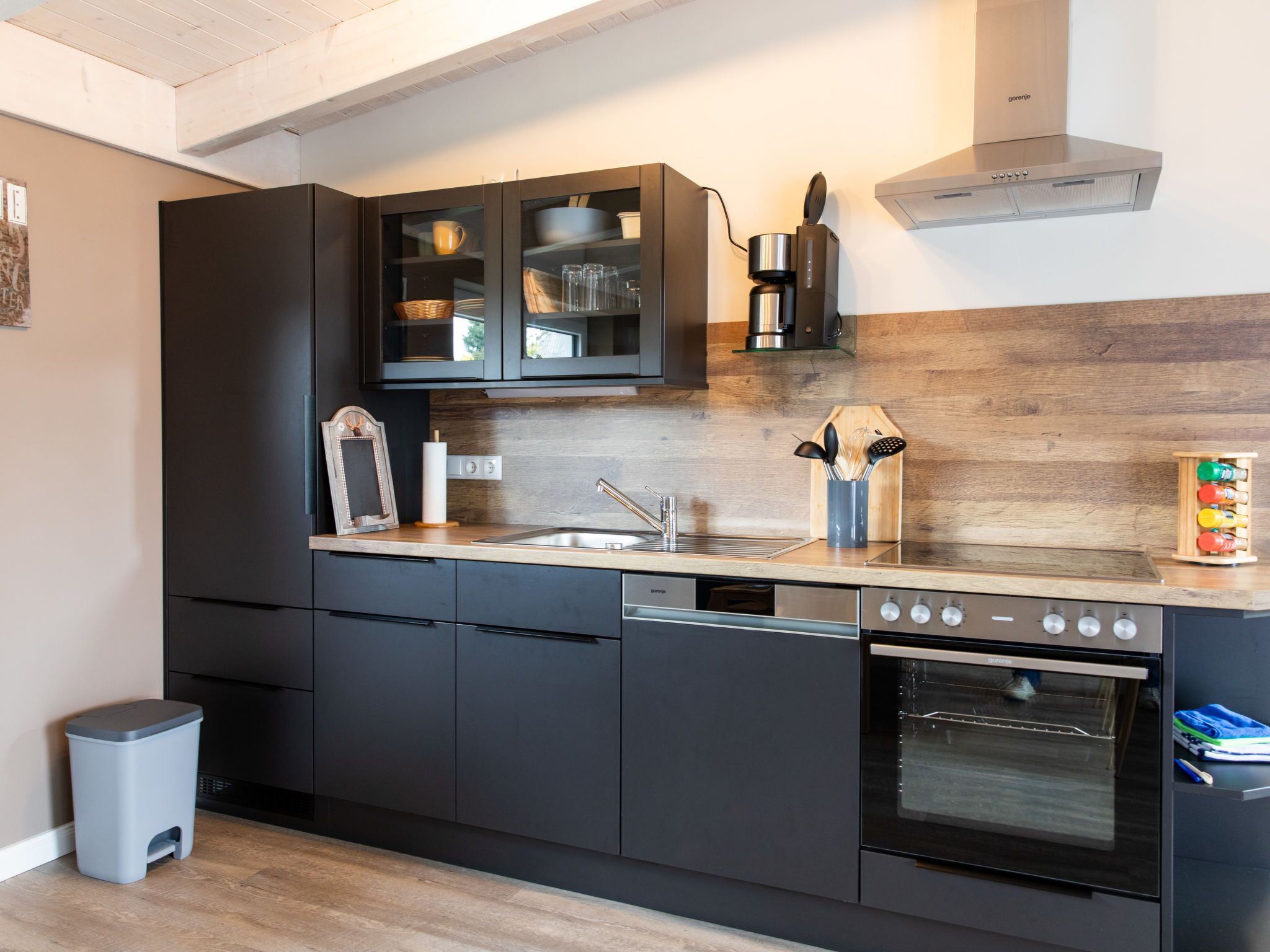 Een moderne keuken met donkere kastjes, een roestvrijstalen spoelbak en een ingebouwde oven.