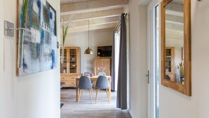 Een moderne eethoek met een houten plafond, een eettafel met stoelen, een kast met glazen deuren en een grote spiegel aan de muur.