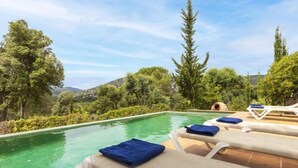 Un espace aménagé au bord de la piscine, avec des chaises longues et une vue sur la végétation et les collines environnantes.