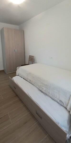 Un dormitorio con una cama grande, un armario de madera y una silla.