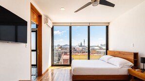 A modern bedroom with a large bed, a TV, and a city view. - Cathedral Fantastic View Loft (Heroica Puebla de Zaragoza)