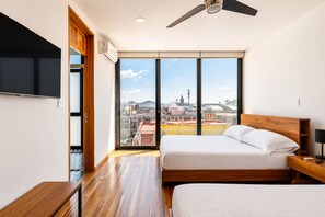 A modern bedroom with a large bed, a TV, and a city view. - Cathedral Fantastic View Loft (Heroica Puebla de Zaragoza)