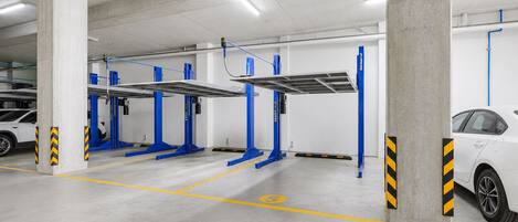 A parking garage with multiple electric vehicle charging stations, concrete pillars, and marked parking spaces.