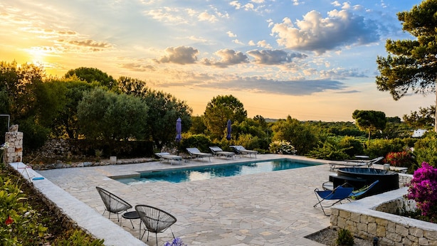 Une piscine avec des chaises longues et une terrasse en pierre.