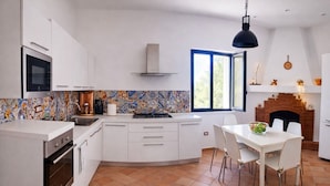 Une cuisine moderne avec des meubles blancs, une cuisinière et un coin repas comprenant une table et des chaises.