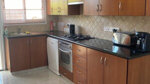 Une cuisine avec des meubles de rangement en bois, une cuisinière, un four à micro-ondes et un lave-vaisselle.