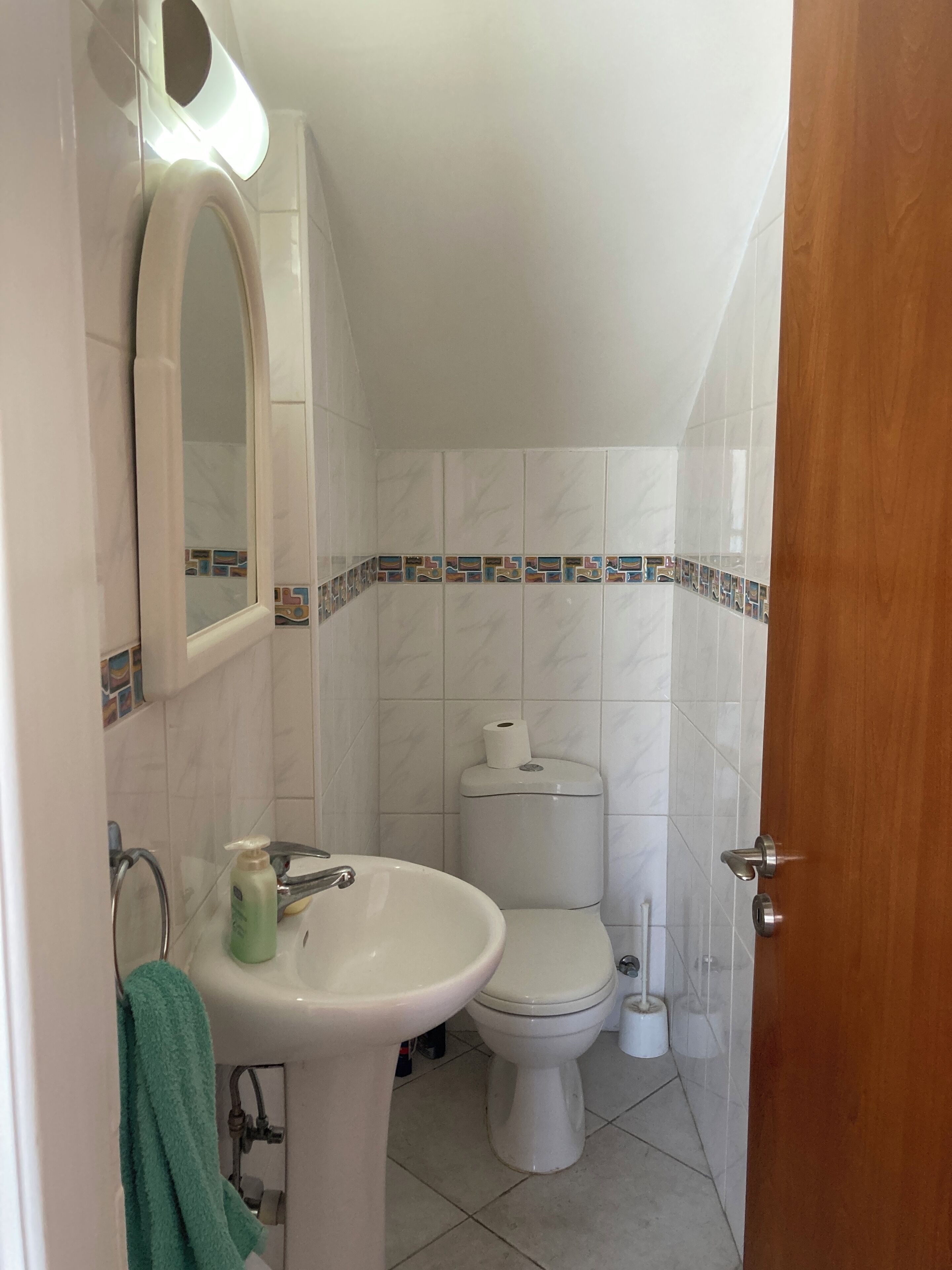 A bathroom with a sink, toilet, and mirror.