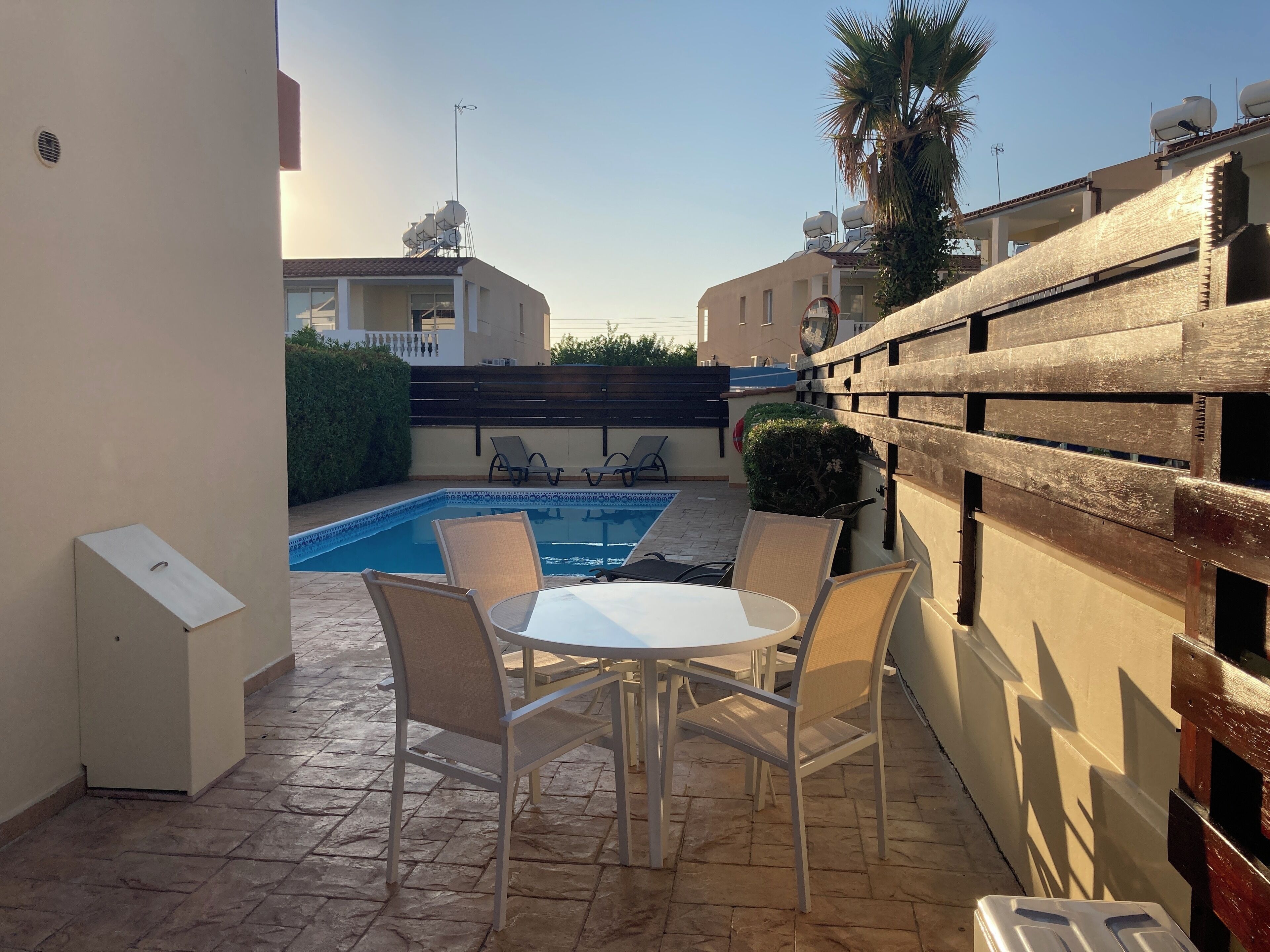 Una zona patio con piscina, sedute all'aperto e recinzione in legno.