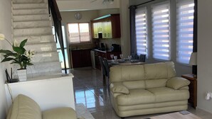 Un vaste espace de vie comprenant un canapé, une table basse et un escalier menant à la cuisine.