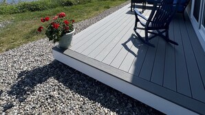 Une terrasse dotée de mobilier d’extérieur, donnant sur un plan d’eau.