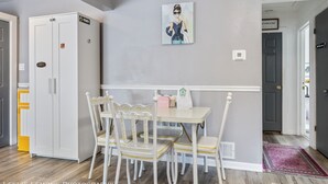 Un área de comedor con una mesa blanca y sillas a juego, un letrero de privado en un armario y un cuadro en la pared.