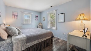 Un dormitorio con cama, mesita de noche, lámpara y decoración en la pared.