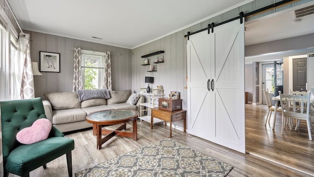Una sala de estar con un sillón verde, un sofá beige, una mesa de centro y un amplio ventanal corredero blanco.