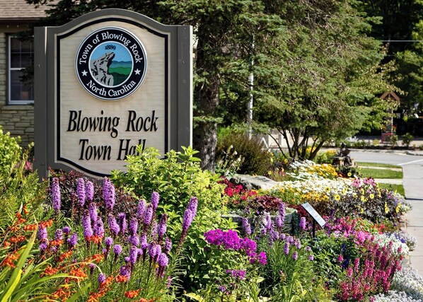 Blowing Rock Town Hall sign features a historic emblem and vibrant flower bed.