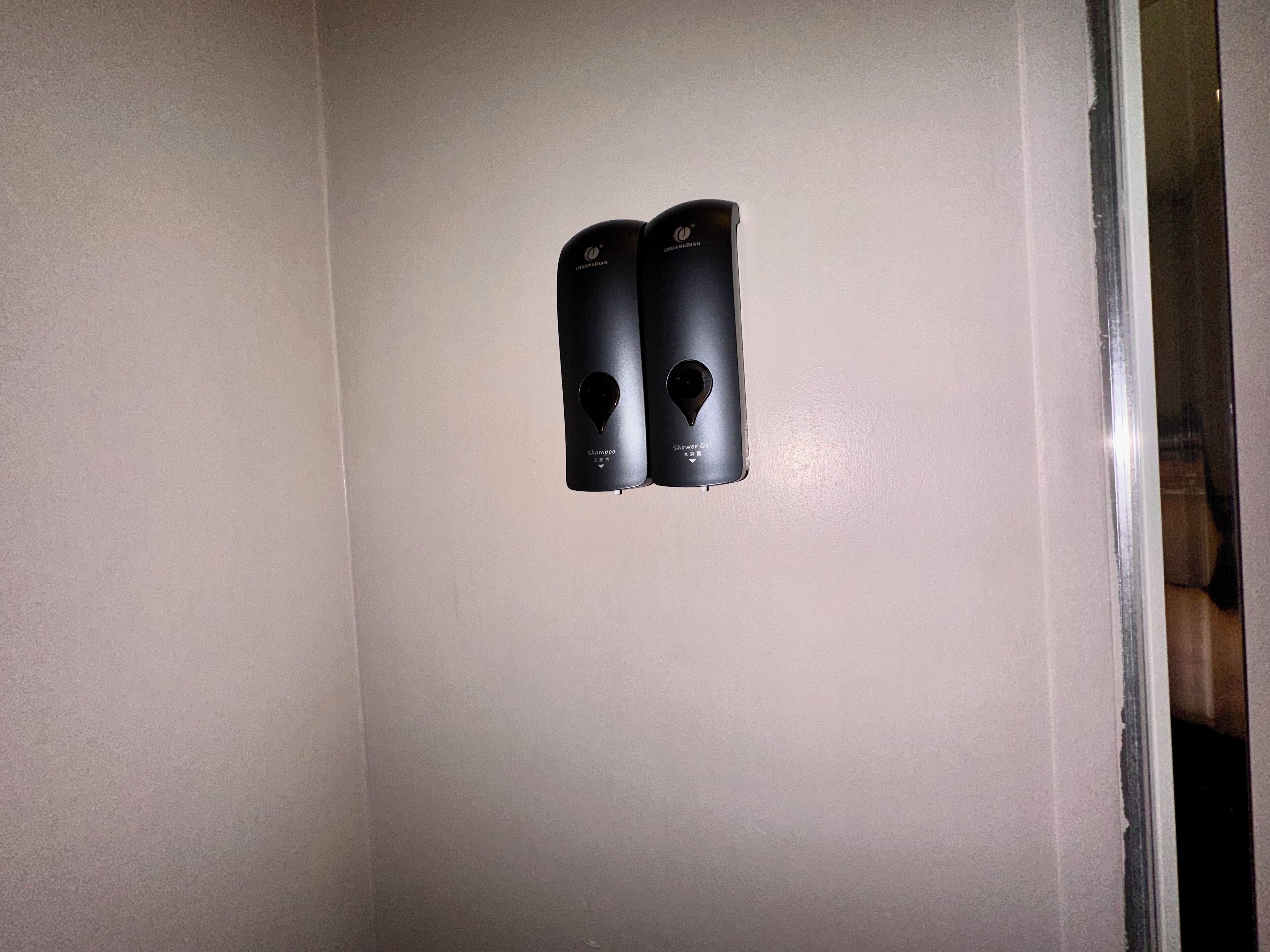A wall-mounted control panel with two buttons labeled "Shampoo" and "Shower Gel".