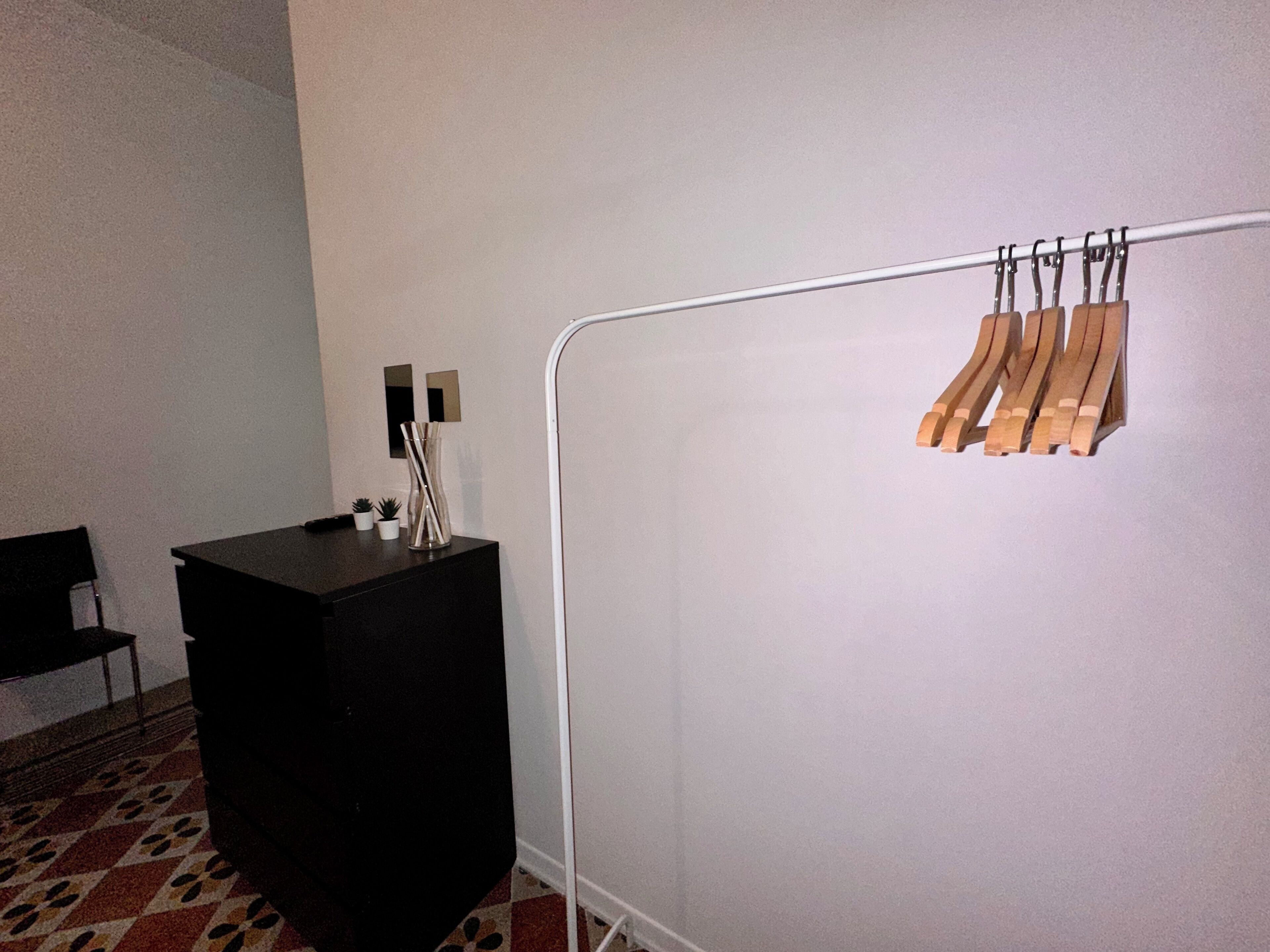A room with a black cabinet, a white wall, and a metal rack with wooden planks.