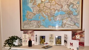 A desk with a framed map, brochures, a plant, and a smartphone. - Mammina Home Napoli - Santa Lucia (Naples)